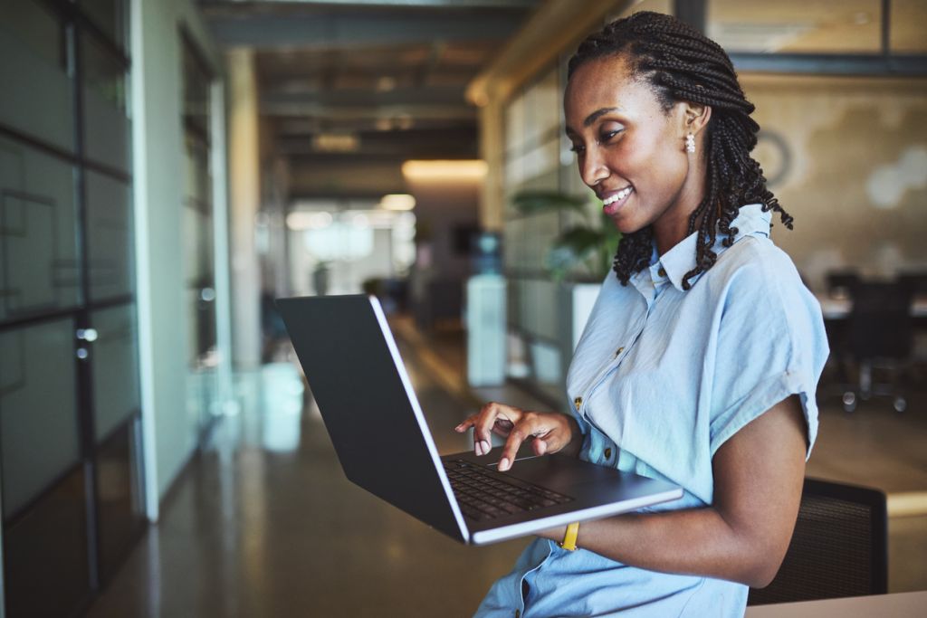 Embracing MyVideoSpot: Stories from Central Bucks School District 1 - MyVideoSpot A woman in a light blue shirt types on a laptop while standing in a modern office hallway.